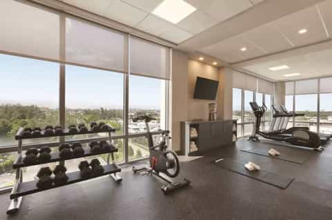 Modern fitness center with dumbbells, exercise bikes, and floor-to-ceiling windows with scenic views