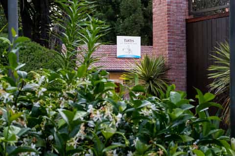 Entrance to a spa facility surrounded by lush green vegetation and brick architecture