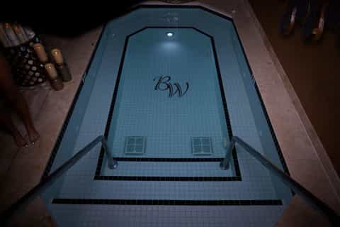 Indoor spa pool with blue tile, logo branding, and ambient lighting