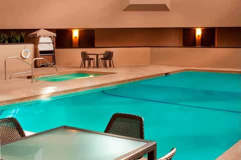 Indoor heated swimming pool with turquoise water, tan deck, and warm amber lighting