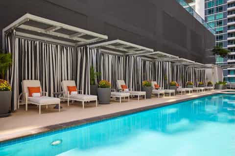 Luxurious pool cabanas with striped curtains and loungers beside a sparkling swimming pool