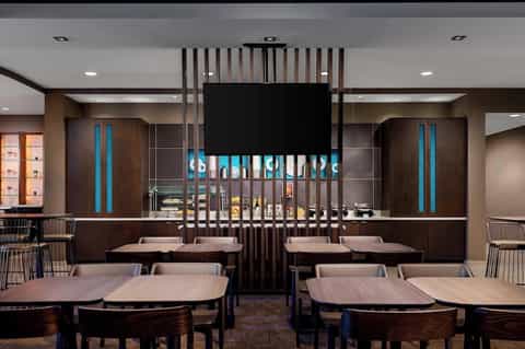 Modern hotel restaurant interior with dark wood design, blue accent lighting, and table seating