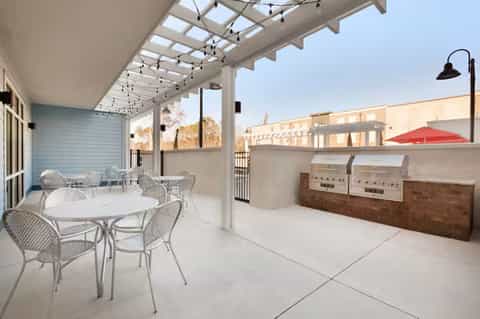 Rooftop terrace with dining table, covered pergola with string lights, and built-in grills