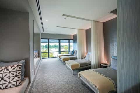 Modern spa relaxation room with multiple lounges, floor-to-ceiling windows, and neutral décor