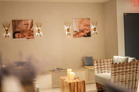 Spa relaxation room with spa imagery on walls, decorative wall sconces, and woven seating furniture