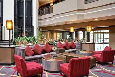 Elegant hotel lobby with high ceilings, red accent chairs, and warm ambient lighting