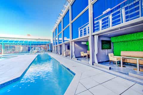Indoor pool facility with lap lanes, blue water, glass walls, and modern lounge seating