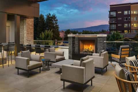 Elevated terrace lounge with fireplace, upholstered seating, and mountain sunset views at dusk