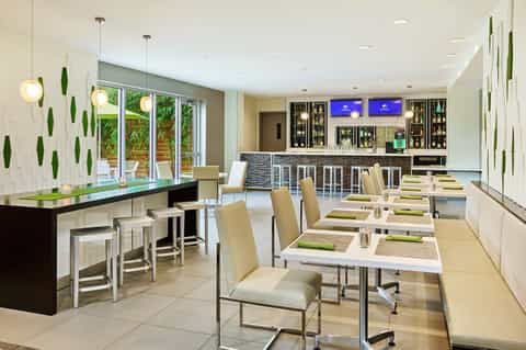 Modern hotel dining room with bar counter, pendant lighting, and green accent wall design