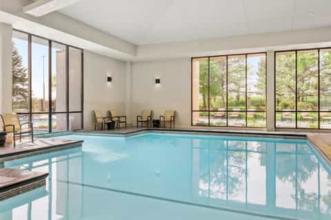 Indoor heated pool with large windows overlooking landscaped grounds and outdoor seating