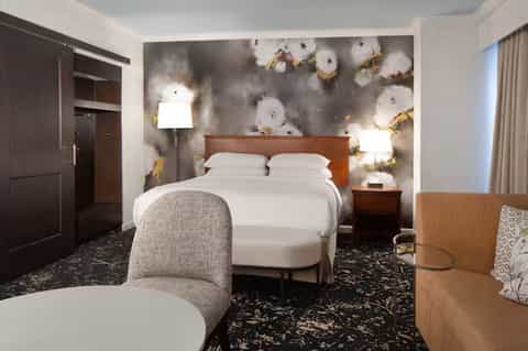 Hotel bedroom with modern artwork headboard, white bedding, and contemporary furnishings