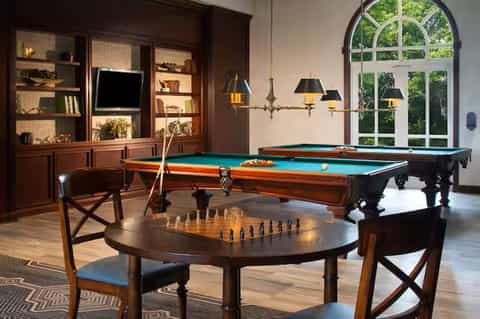 Luxury recreation room with billiards tables, chess set, and wood cabinetry