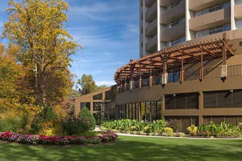 Modern resort exterior with landscaped gardens, wooden pergola, and apartment building facade
