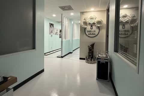 Modern salon or spa corridor with light blue and white walls, rose wall art, and professional signage