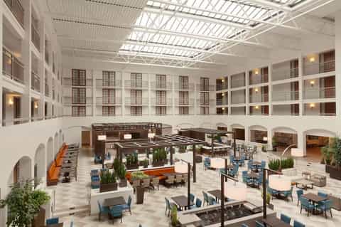 Modern hotel atrium lobby with white railings, skylights, and contemporary seating areas