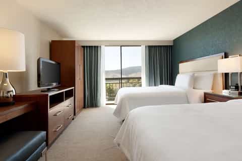 Modern hotel double room with dark wood furniture, mountain views through windows, and contemporary design