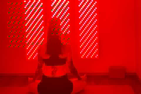 Red neon light installation with silhouette figure in center and geometric patterns on walls