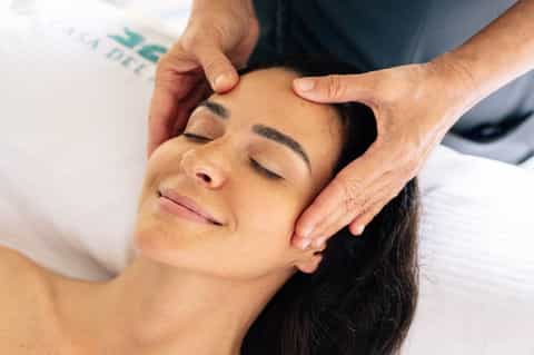 Spa therapist giving head and temple massage to relaxed female guest