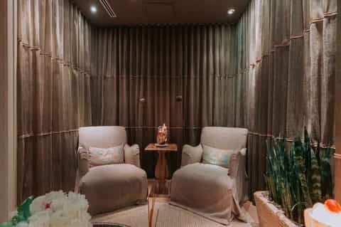 Luxury spa relaxation room with two beige armchairs, ambient drapes, and soft lighting