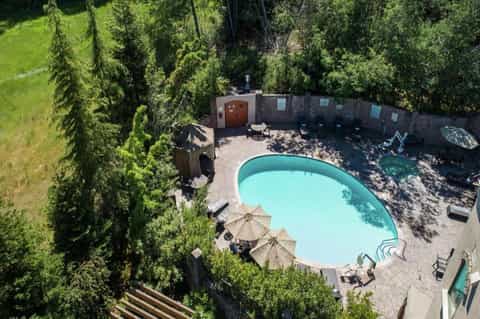 Aerial view of resort pool surrounded by tall cypress trees and stone privacy walls