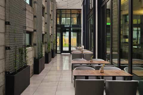 Contemporary outdoor dining terrace with wooden tables, seating, and large windows