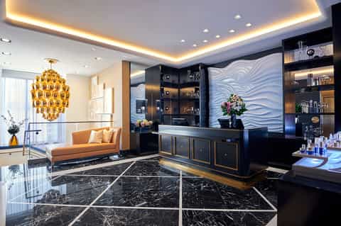 Luxury hotel lobby with black marble floors, gold chandelier, and modern furnishings