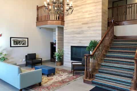 Hotel atrium with wooden railings, chandelier, multi-level mezzanine, and contemporary seating area