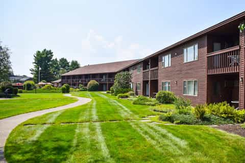 Resort exterior showing brown wooden buildings with manicured lawns and landscaped grounds