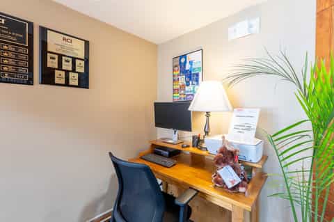 Business center desk with computer, lamp, awards plaques, and green plant decor