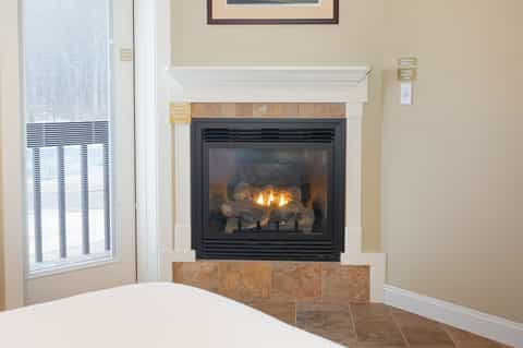Hotel guest room with fireplace, bed, and bright window