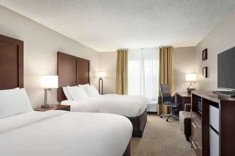 Hotel guest room with two queen beds, neutral tones, and modern furnishings