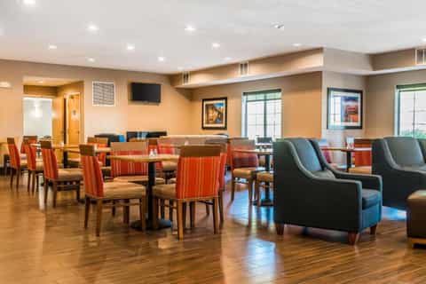 Hotel lounge with striped orange chairs, dark blue seating, warm lighting, and wood flooring