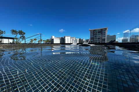 Rooftop pool with blue tile deck, lounge chairs, and city skyline view