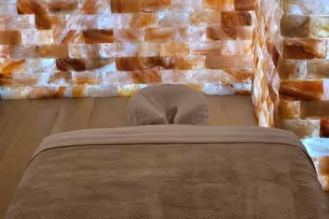 Luxury hotel bedroom with stone accent wall, wooden floors, and neutral bedding