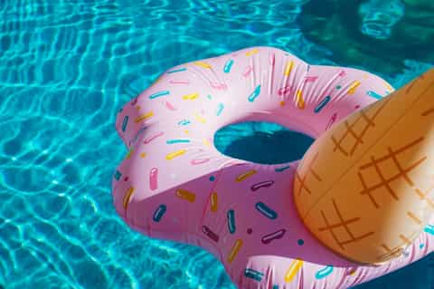 Pink and orange inflatable pool floats in bright turquoise swimming pool water