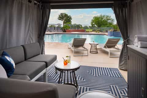 Luxury cabana with gray furniture overlooking turquoise resort pool
