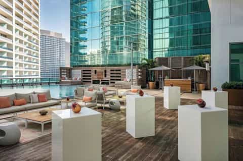 Rooftop lounge with modern seating, fire pit, and skyline view surrounded by high-rise buildings