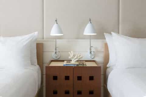 Twin beds with beige headboard, white pillows, and wooden nightstand