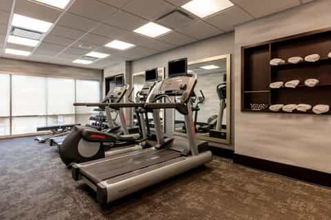 Fitness center with cardio equipment, treadmill, exercise bike, and wall mirror