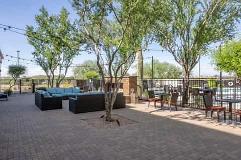 Rooftop patio with turquoise lounge seating, mature trees, and city views beyond railing