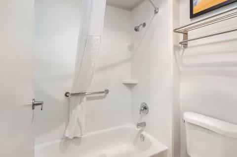 Clean white bathroom with bathtub, shower, towel rack, and brushed metal fixtures