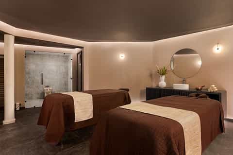 Twin massage beds in spa treatment room with brown quilted linens and modern minimalist design