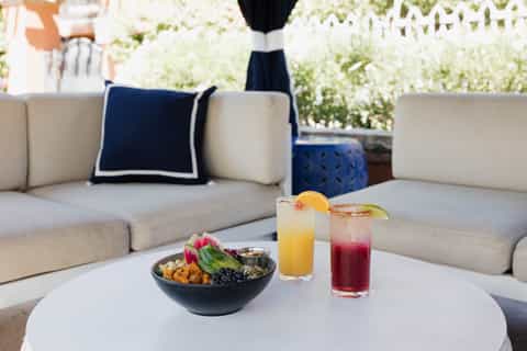 Outdoor lounge seating with fresh fruit bowl and colorful cocktails on white coffee table