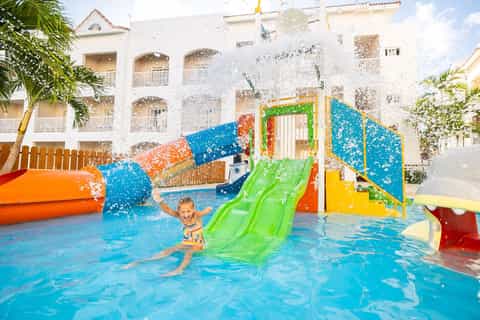 Colorful kids' water park with bright slides, splash pad, and historic colonial building