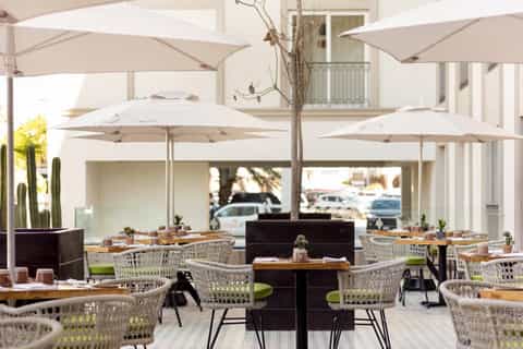 Outdoor dining patio with woven chairs, umbrellas, and modern architecture