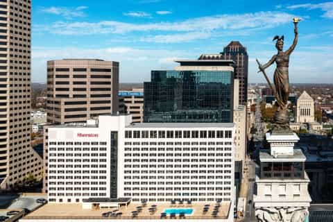 Downtown Sheraton hotel rooftop pool overlooking urban skyline with statue and city buildings