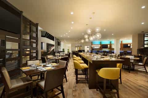Contemporary fine dining restaurant with warm lighting, modern chandeliers, and elegant table settings