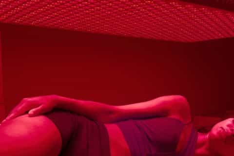 Person lying in bright pink/red hammock or relaxation pod under red tent-like fabric