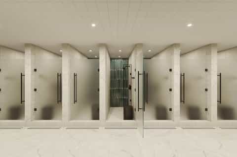 Contemporary fitness center with multiple shower stalls featuring frosted glass enclosures and marble flooring