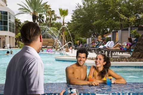 Guests enjoying drinks at resort pool bar with lush landscaping and tropical atmosphere